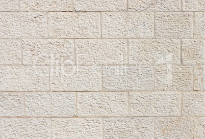 vertical wall built of beige stone blocks