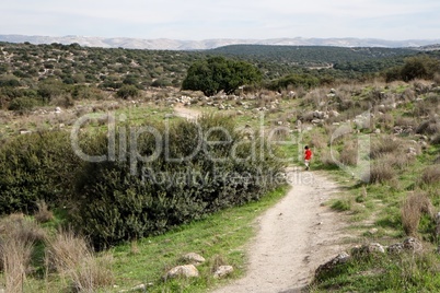 Lonely little boy walks along the trail among hills outdoor