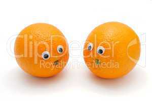 Two funny orange fruits with eyes on white background