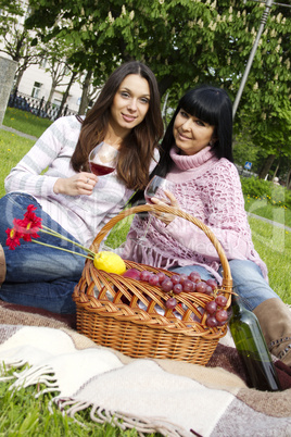 Mother and daughter drinking wine outdoors
