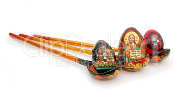 Three Easter eggs in Russian wooden hand-painted spoons with long handles on white background