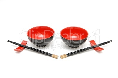 Two sets of chopsticks on stands and the red and black Japanese bowls