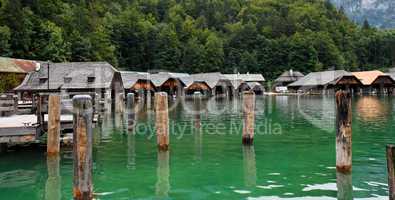 Wooden boat houses and mooring posts on green lake water