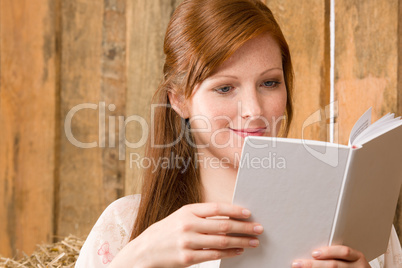 Young romantic woman in barn reading book