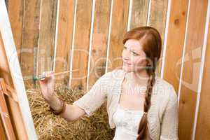 Red-hair romantic woman painting in barn