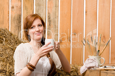 Young romantic woman in barn holding cup
