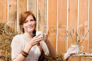 Young romantic woman in barn holding cup