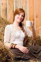 Young romantic woman in barn holding cup