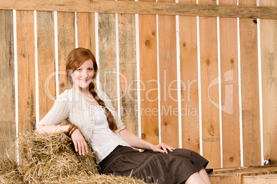 Romantic young woman sitting on hay barn