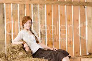 Romantic young woman sitting on hay barn