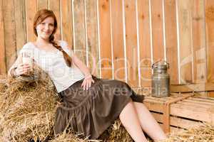 Young healthy woman hold glass of milk in barn