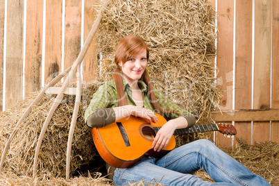 Young country woman play guitar in barn