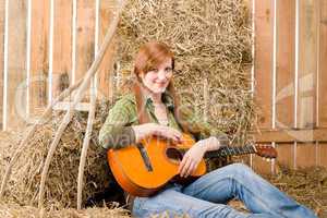 Young country woman play guitar in barn