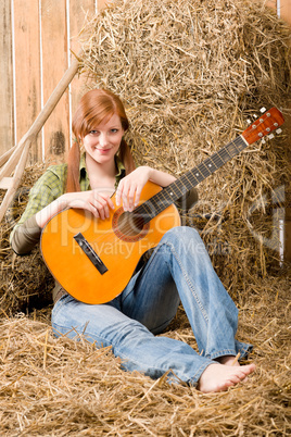 Young country woman sitting on hay with guitar
