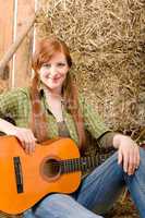 Young country woman sitting on hay with guitar