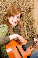 Young country woman playing guitar in barn