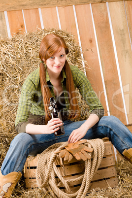 Provocative young cowgirl drink beer in barn