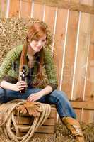 Provocative young cowgirl drink beer in barn