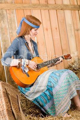 Young hippie woman play guitar in barn