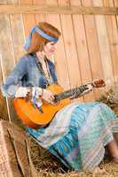 Young hippie woman play guitar in barn