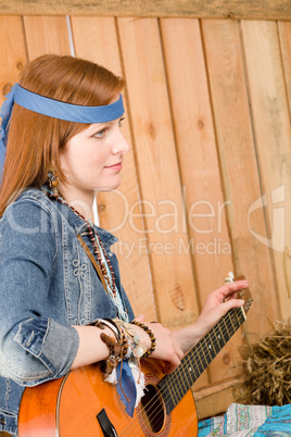 Young country woman playing guitar in barn