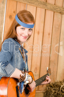 Young country woman playing guitar in barn