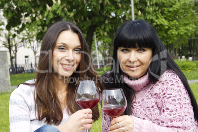 Mother and daughter drinking wine outdoors