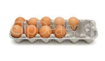 Nine brown eggs in a paper box isolated