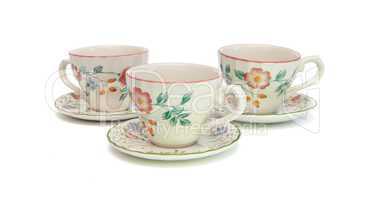 White tea service of three cups with saucers painted with dogroses isolated