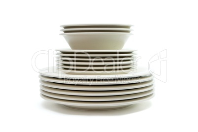 Stack of plain beige dinner plates, soup plates and saucers isolated
