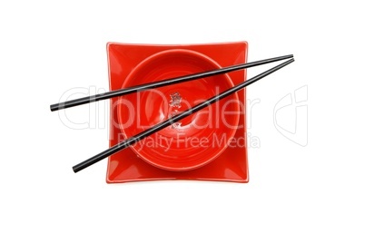 Black chopsticks on red Japanese bowl  and square plate top view isolated