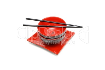 Black chopsticks on two red and black Japanese bowls and square plate isolated