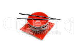 Black chopsticks on two red and black Japanese bowls and square plate isolated