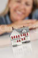 Smiling Woman Behind Model House on a White Surface