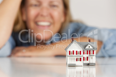 Smiling Woman Behind Model House on a White Surface