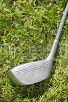 Golf club driver laying in grass, concept photography