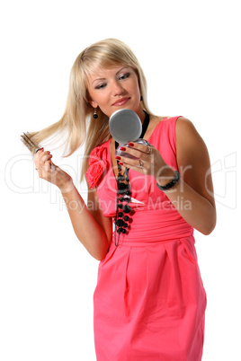 Beautiful young girl combing her hair before a mirror