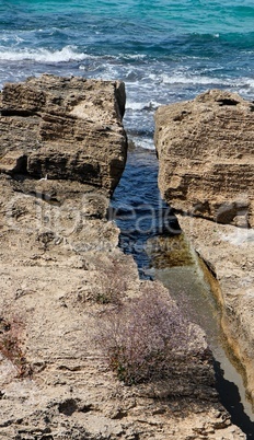 Narrow crack in the rocks at sea coast in bright summer day