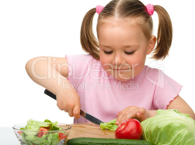 Little girl is cutting carrot for salad