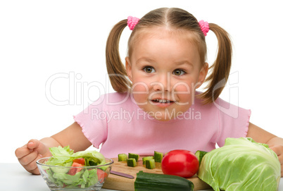 Little girl is cutting carrot for salad