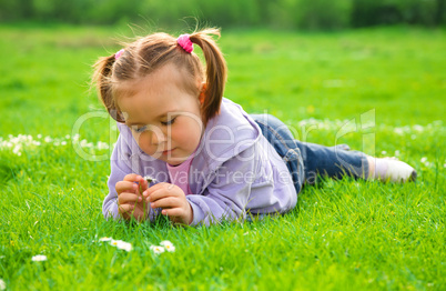 Little girl is laying on green meadow