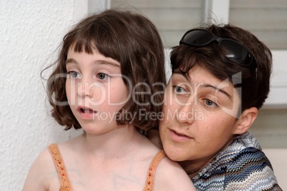 Mother and cute little daugher watch TV in great concentration