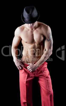 athletic man posing nude in dark with hat