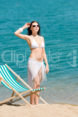 Summer toned woman sunbathing on beach in bikini
