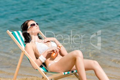 Summer young woman sunbathing in bikini suncream