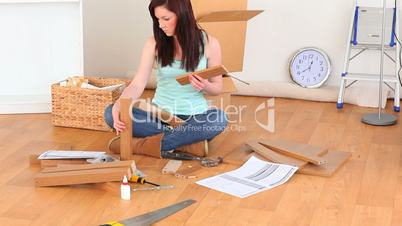 junge Frau baut  ein Möbelstück zusammen