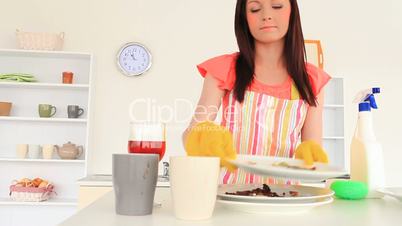 junge Frau räumt in der Küche das Geschirr weg