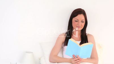 junge Frau sitzt im Bett und ließt ein Buch