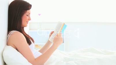 junge Frau sitzt im Bett und ließt ein Buch