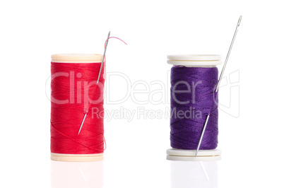 Two red and purple thread bobbin and needle